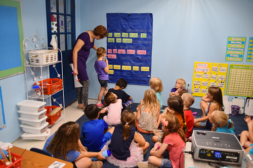 teacher helping students at table teacher helping students at table